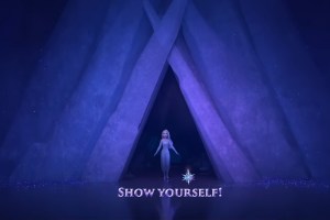 The image is a shot from the movie Frozen II, where Elsa enters the cave following the sound of the siren. It has the words 'Show Yourself!' and a snowflake beneath Elsa.