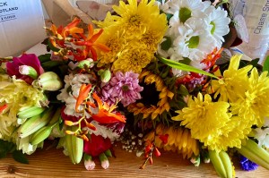 The picture shows an array of cut flowers, including lilies, daisies, sunflowers, in hues of white, yellow and orange, ready to be made into bouquets.