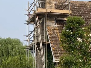The picture shows the side of a house with scaffolding around the chimney